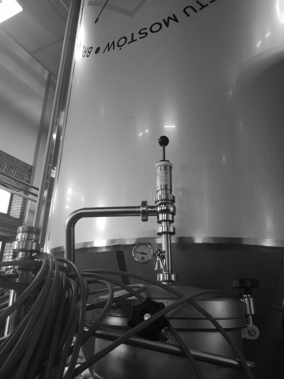 Shiny industrial fermentation tanks with piping inside a production facility.