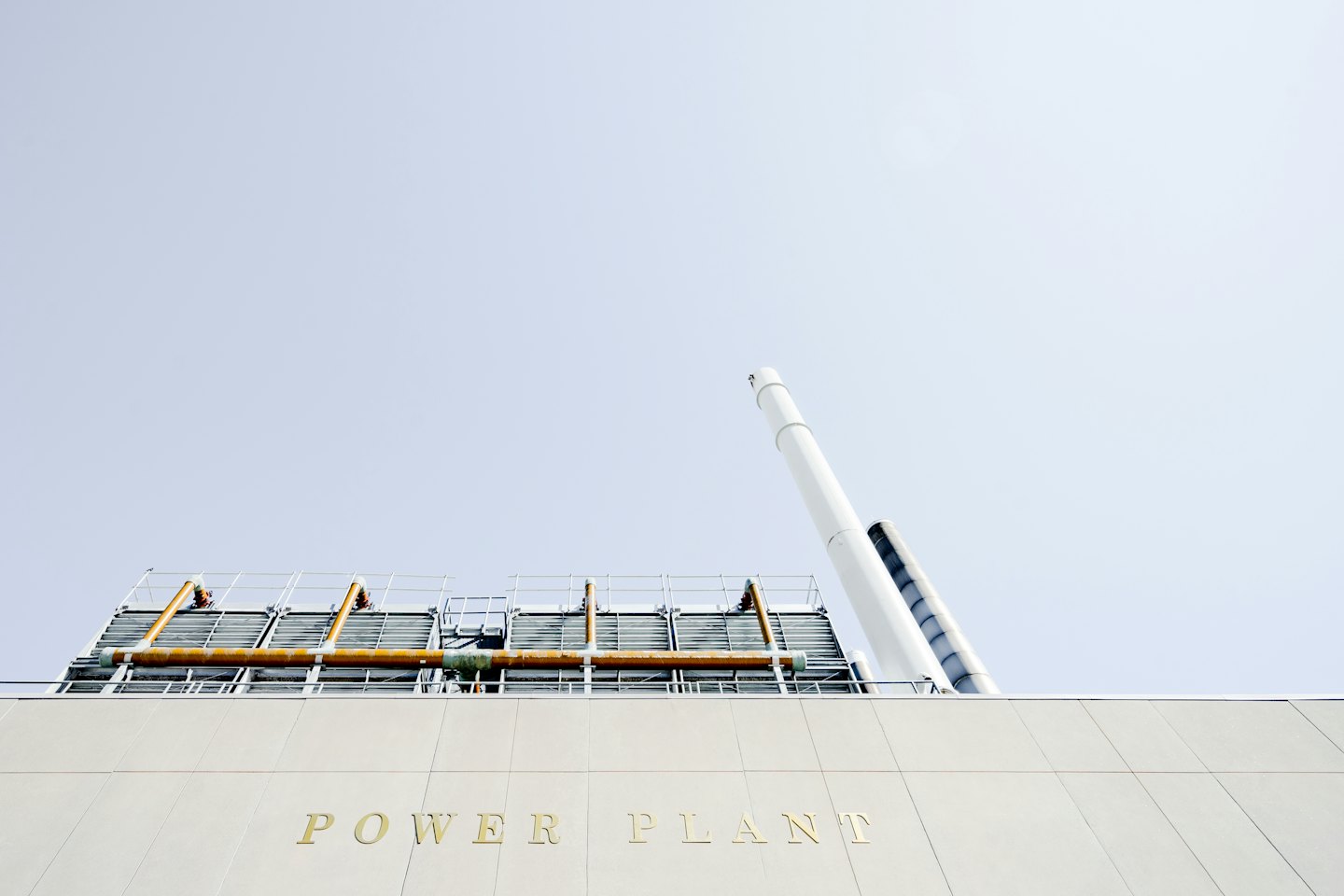 Modern power plant facade with gold lettering and white smokestacks.