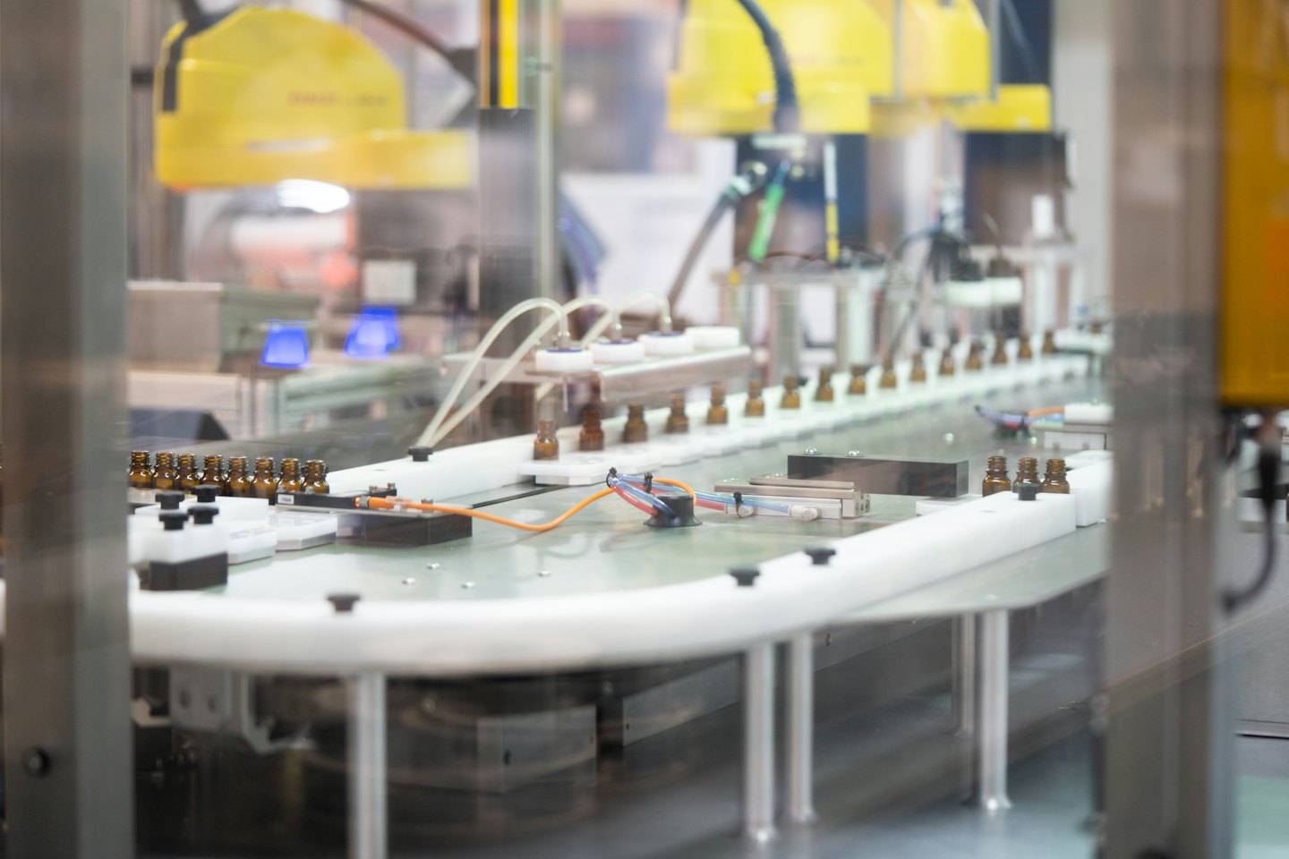 Amber bottles move along a conveyor belt in a factory.