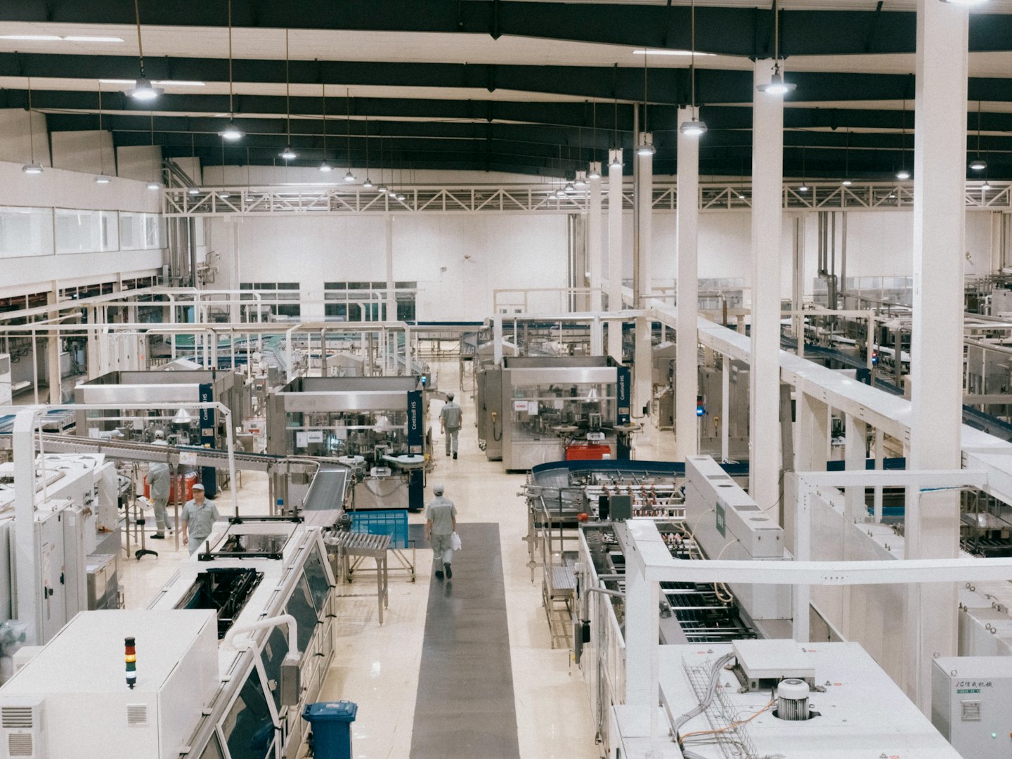 Workers moving between automated machinery on a production line.